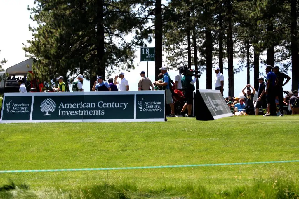 a group of people standing around a green golf course