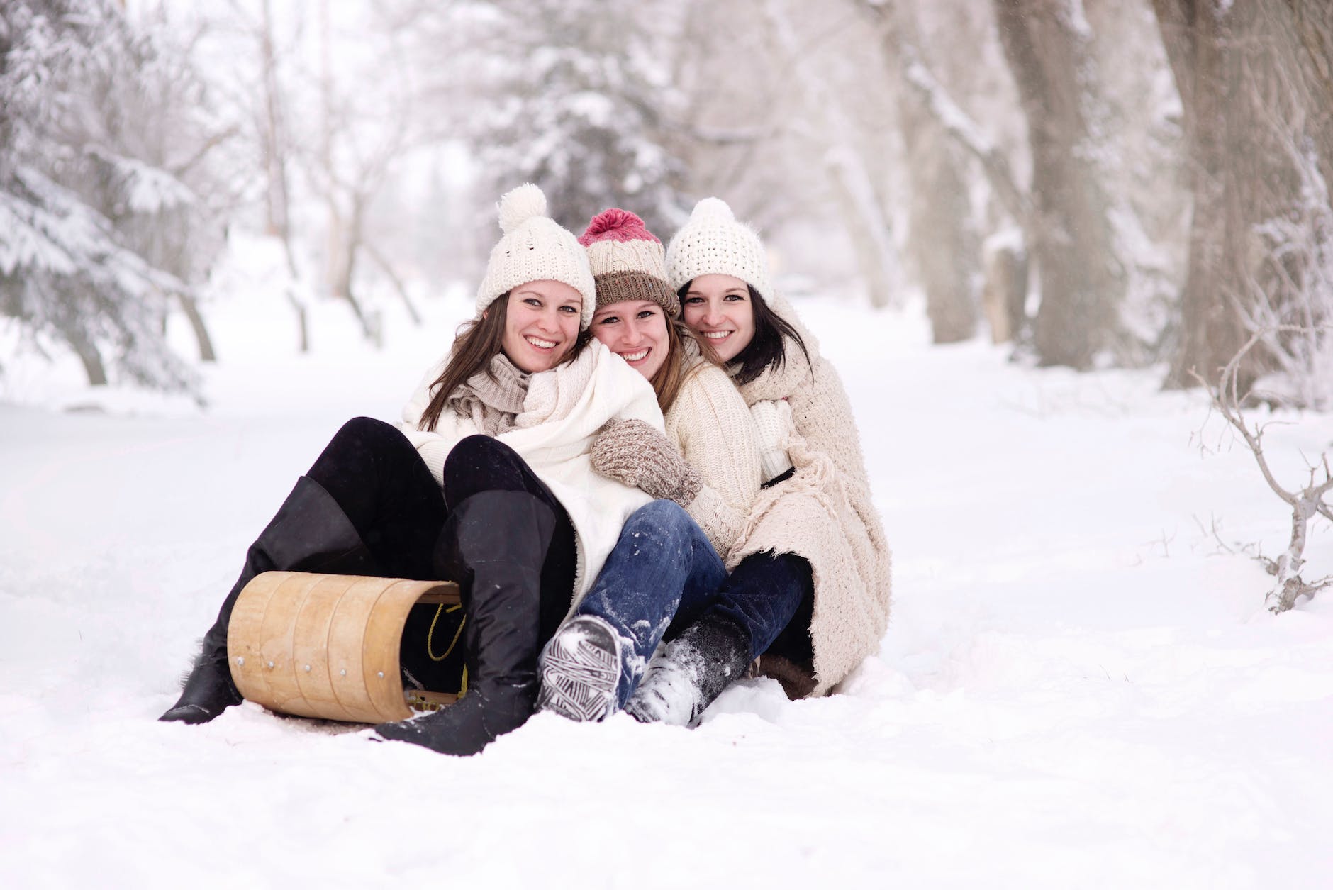 three women sitting on snow covered ground during day