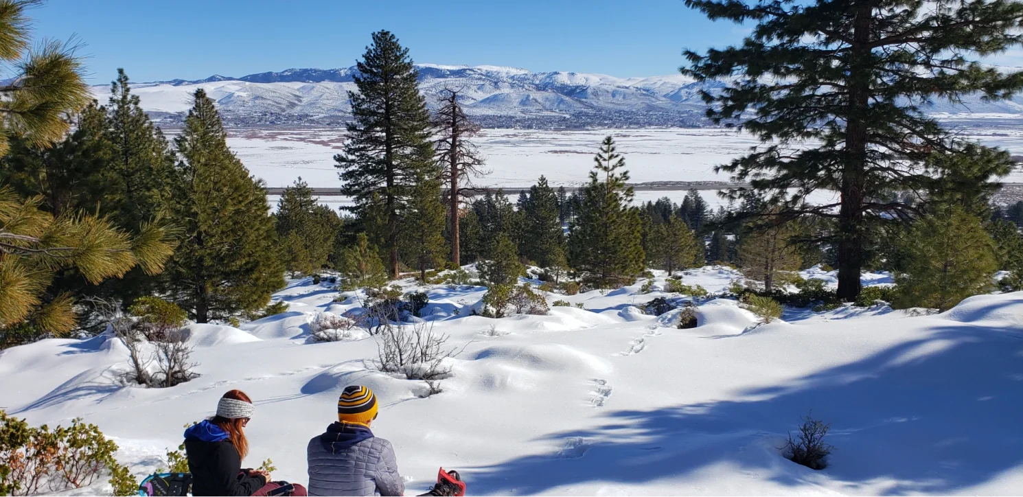 couple sitting in snow looking over snow covered valley