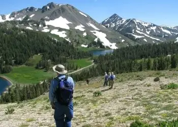 Five hikers roaming the mountainous terrain of the Sierra Nevada on a sunny day. They are wearing book bags.