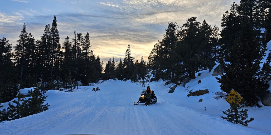 Man Snowmobiling in the Sierra at sun set near Blue lake California