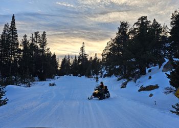 Man Snowmobiling in the Sierra at sun set near Blue lake California