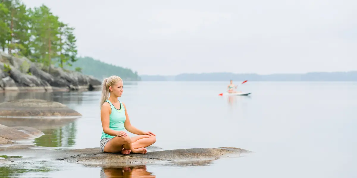 Girl doing Yoga Lake shore with kayak on the lake