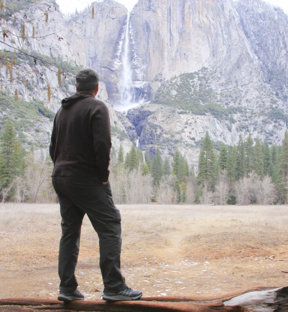 Guy in Yosemite looking across at Yosemite falls wearing Royal Robbins pants and top