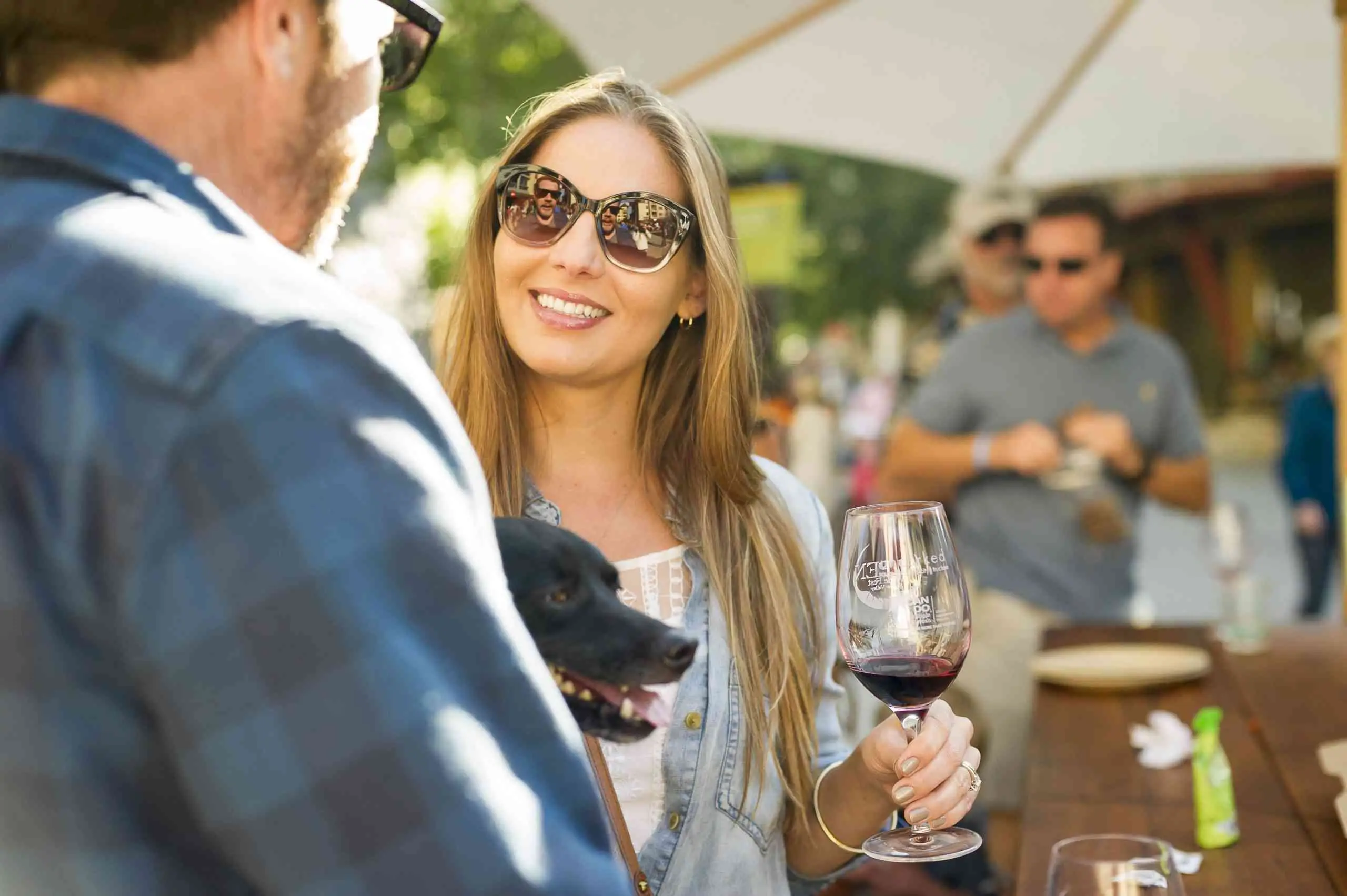 Lady drinking wine with dog adn crowd