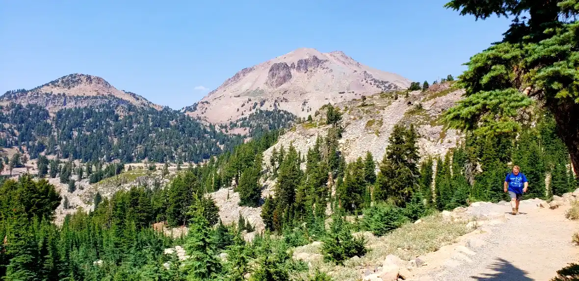 man walking bumpass hell trail with lassen peak in background